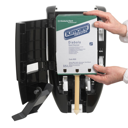 Eine Person setzt eine 3,5-Liter-KIMCARE INDUSTRIE DIABOLO Waschlotion-Kartusche der Kimberly-Clark GmbH in einen schwarzen Wandspender ein und benutzt beide Hände, um die orangefarbene Nachfüllung für eine schonende Handreinigung einzustellen.