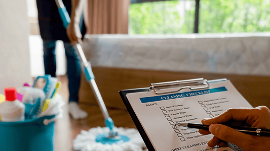 eine Checkliste wird angekreuzt während im Hintergrund mit einem Wischmopp ein Boden gewischt wird und daneben steht ein Putzeimer voll mit Reinigungsmittel und Reinigungsuntensilien