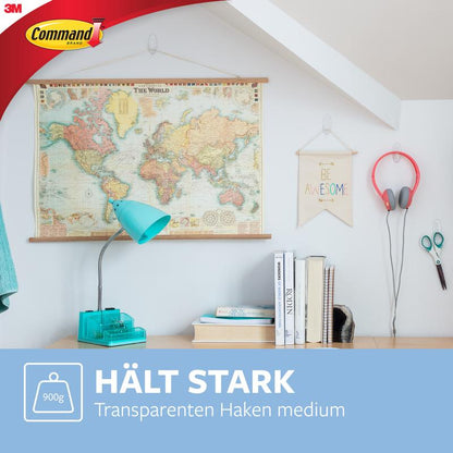 Valoisassa huoneessa roikkuu maailmankartta, "Be Awesome"-kyltti ja kuulokkeet 3M Deutschland GmbH Command™ Koukku M, keskikokoinen, läpinäkyvä (17091CLR), työpöydän yläpuolella, jossa on sininen lamppu ja kirjoja. Saksankielinen teksti: "Pitää vahvasti. Jäämätön. Läpinäkyvä keskikokoinen koukku."