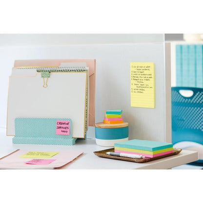 Siisti toimistopöytä, jossa on kansioita, muistilehtiö, värikkäitä muistilappuja, kynä, tabletti ja pyöreä säiliö. Väliseinällä on keltainen Post-it® Notes -muistilappu suurikokoisena (101 mm x 152 mm) 3M Deutschland GmbH:lta, taustalla siniset tuolit ja kaapit.