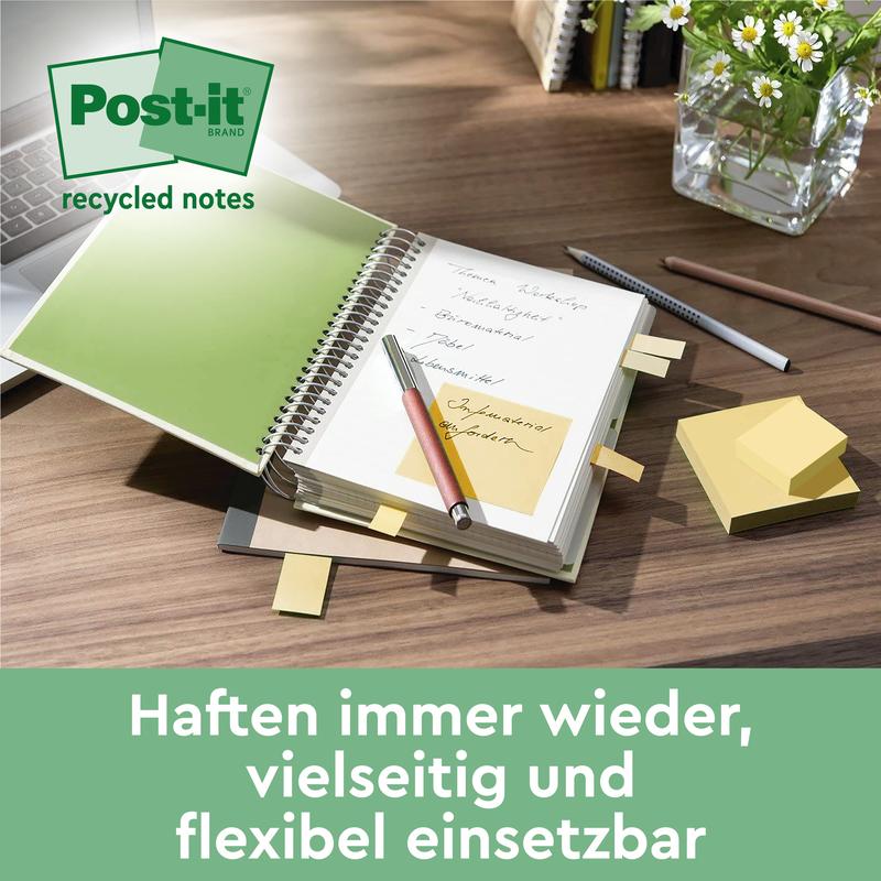 Työpöydällä on Post-it® Recycling Z-Notes -lohko (76x76mm, 100 arkkia, 100 % PEFC) 3M Deutschland GmbH:lta, muistilappuja avoimessa muistikirjassa, kynä, hajallaan olevia muistiinpanoja, lasi vettä ja ruukkukasvi. "Tarttuu aina uudelleen - monipuolinen & joustava."