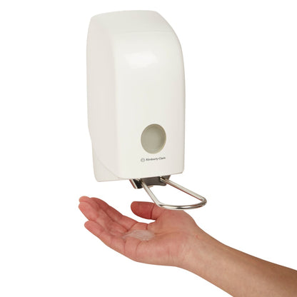 Käsi pidetään seinään kiinnitetyn Aquarius™-pesunesteannostelijan (valkoinen, 1 litra) alla Kimberly-Clark GmbH:lta, joka annostelee nestettä helposti ja hygieenisesti kämmenelle.