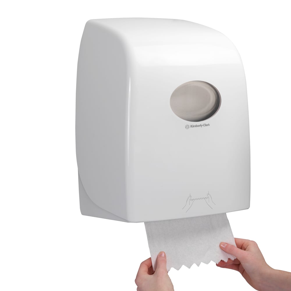Joku vetää Scott® ESSENTIAL™ käsipyyherullan arkkia valkoisesta, seinään kiinnitetystä annostelijasta Kimberly-Clark GmbH:lta, jonka läpinäkyvä ikkuna paljastaa sisällä olevat käsipyyherullat.