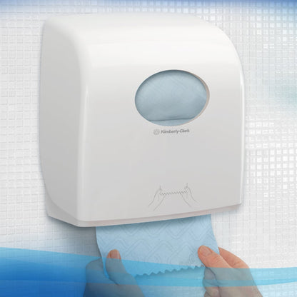 Henkilö vetää sinistä Scott® Essential™ käsipyyherullaa valkoisesta annostelijasta Kimberly-Clark GmbH:lta, joka on kiinnitetty kaakeloituun seinään, jossa on pyöreä ikkuna, joka näyttää sisällä olevat käsipyyhkeet ja pyyhkeiden annosteluohjeen.