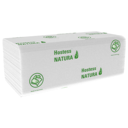 Ein Stapel weißer, gefalteter Hostess™ NATURA™ Handtücher (Kimberly-Clark GmbH), Groß, 20 x 84 Blatt, mit grünem Branding und Daumen hoch Symbol. Made in Germany-ideale Papierhandtücher für öffentliche Bereiche. 20 Päckchen pro Karton.