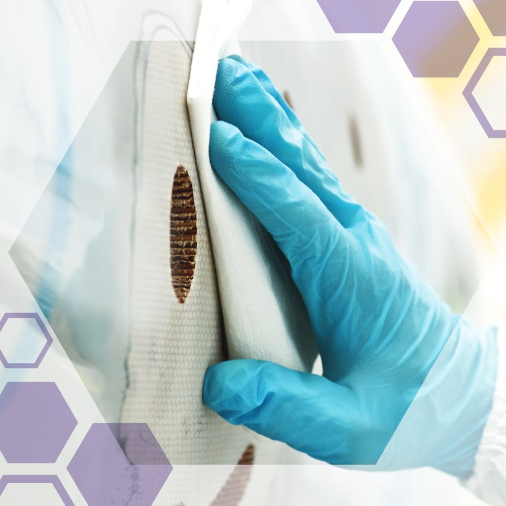 Eine Hand in einem blauen Handschuh reinigt braune Flecken von einer weißen Oberfläche mit Kimberly-Clark GmbH Kimtech® Science Präzisionswischtüchern (200 Blatt, weiß), ideal für empfindliche Oberflächen. Sechseckige Grafiken erscheinen in den Bildecken.