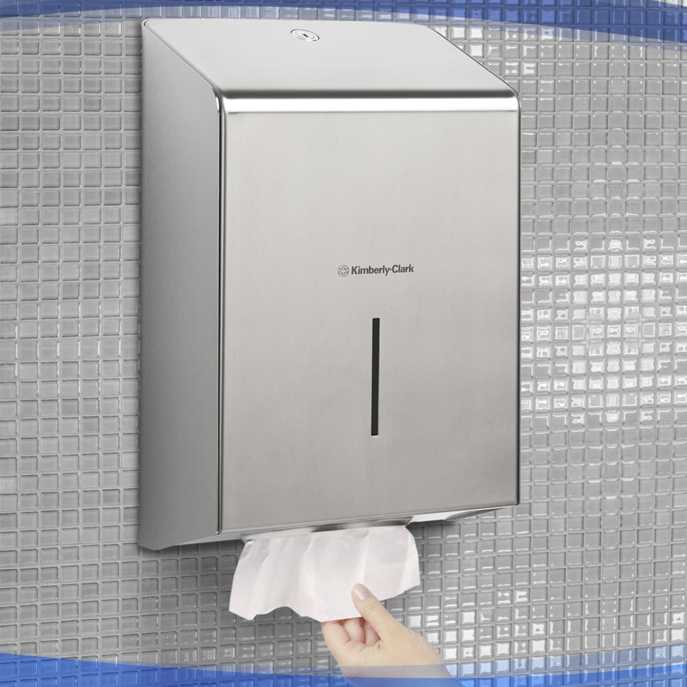 Eine Hand zieht ein Papierhandtuch aus dem Kimberly-Clark Professional™ Handtuchspender aus Edelstahl (1 Spender), hygienisch montiert an einer gefliesten Wand.