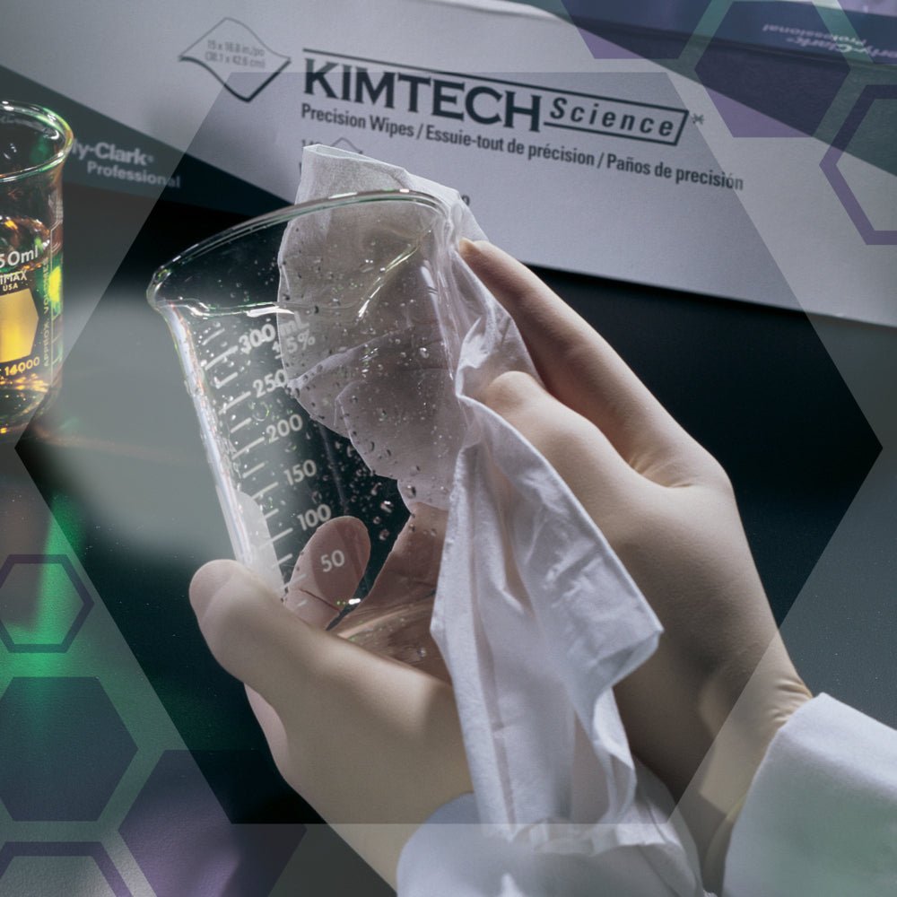Hansikas käsi pyyhkii valkoisella liinalla lasimittalasia Kimberly-Clark GmbH:n Kimtech® Science Precision -liinapakkauksen (Suuri, Valkoinen, 15x196 liinaa) vieressä. Taustalla näkyy laboratoriolaitteita ja muita laboratorioliinoja.