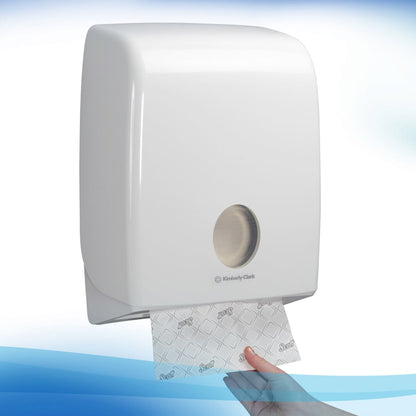 Valkoinen, seinään kiinnitetty Kimberly-Clark GmbH:n annostelija jakaa yhden arkin Scott® käsipyyhkeitä - Narrow-Fold / Valkoinen metallisen etuaukon kautta ja varmistaa näin hygieenisen käsien kuivaamisen jokaisella vedolla.