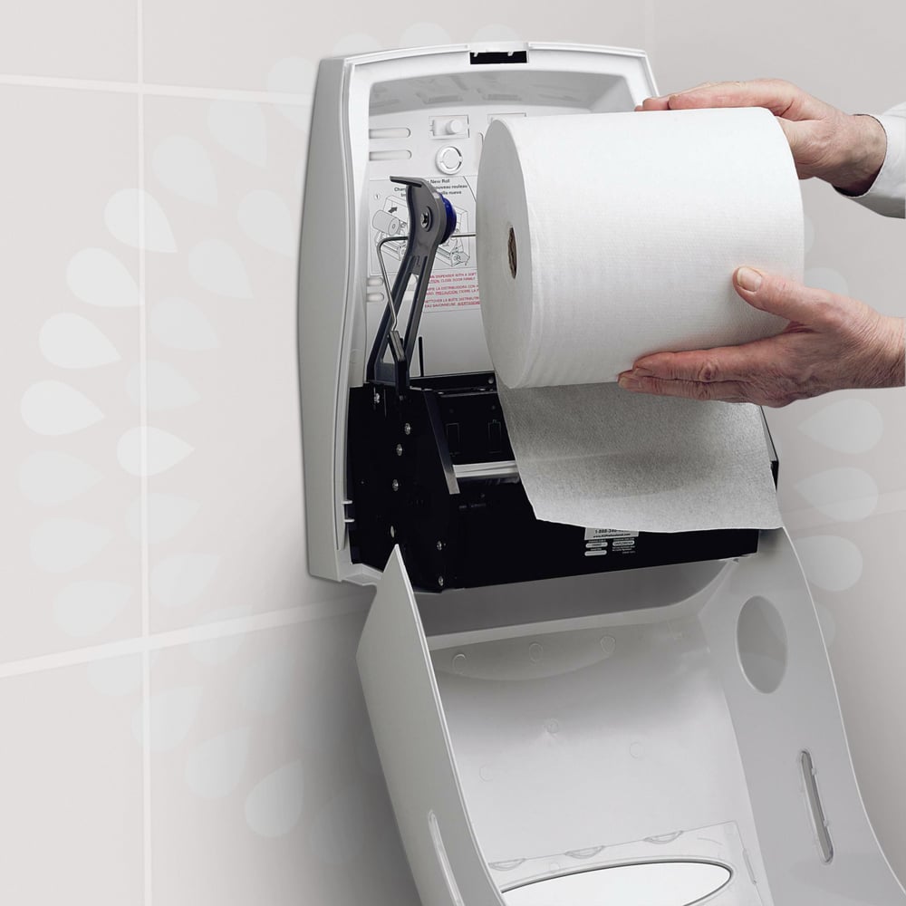 Henkilö asettaa Kimberly-Clark GmbH:n Kleenex® Ultra™ -käsipyyherullan valkoiseen, avoimeen seinäannostelijaan wc:ssä varmistaakseen hygieenisen käsien kuivaamisen. Annostelijan kannessa on ohje painettuna.