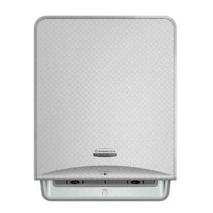 Hopeinen mosaiikki, seinälle asennettava Kimberly-Clark Professional™ Icon™ elektroninen No Touch-Loose Module -rulla Kimberly-Clark GmbH:ltä, jossa on kuvioitu etulevy, keskellä logo ja alaosassa aukko kosketusvapaata pyyhejakelua varten.