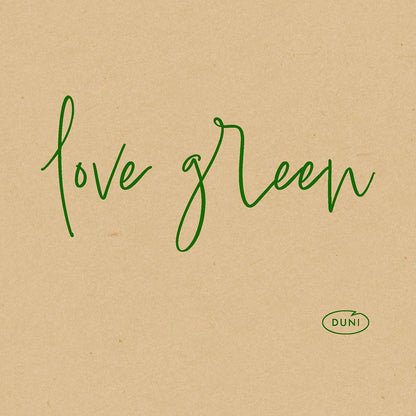 Vihreä kursivoitu teksti "love green" näkyy ruskealla paperitaustalla. Oikeassa alakulmassa on pieni vihreä soikea logo, jossa lukee "DUNI", joka korostaa Bio-Dunisoft-Serv. 20x20cm ympäristöystävällisiä lautasliinoja Duni GmbH:lta.