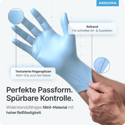 Eine Hand zieht einen hellblauen ARNOMED NITRIL ICE BLUE Einmalhandschuh der ARNOWA GmbH an. Der Nitrilhandschuh hat eine Rollstulpe, strukturierte Fingerspitzen, ist latexfrei, sitzt perfekt, greift auch bei Nässe gut und ist reißfest.