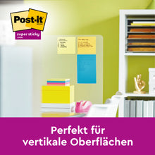 Ein übersichtlicher Raumteiler zeigt den Post-it® Z-Notes Dispenser XL, Schwarz mit großen, linierten, gelben Post-it® Super Sticky Z-Notes (101mm x 101mm) der 3M Deutschland GmbH in einem Büro. Deutscher Text: "Perfekt für vertikale Oberflächen.