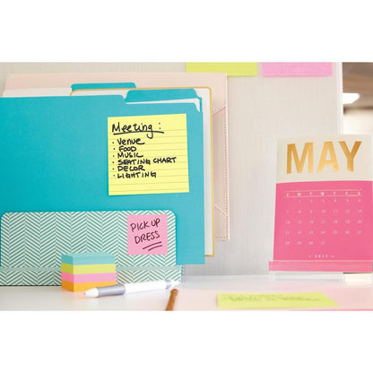 Työalue, jossa on 3M Deutschland GmbH:n Post-it® Notes -muistilappuja suurikokoisena, keltaisena (101 mm x 152 mm), kansioita, roosanvärinen kultainen pöytäkalenteri toukokuulle 2017 sekä värikkäitä muistilappuja ja papereita. Yhdessä paperissa on "Meeting"-aiheita, toisessa lukee "PICK UP DRESS".