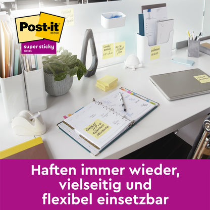 Moderni pöytä, jossa on esineitä 3M Deutschland GmbH:n Post-it® Super Sticky 100% kierrätysmuistilapuilla (47,6x47,6 mm, 70 arkkia/lohko, 100% PEFC). Saksankielinen teksti: "Tarttuu aina uudelleen, monipuolinen ja joustava."
