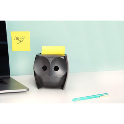 Ein schwarzer Post-it® Z-Zettelspender "Eule" (3M Deutschland GmbH) mit gelben Super Sticky Z-Zetteln steht auf einem weißen Schreibtisch, daneben ein Laptop und ein blauer Stift. An der Wand hängt ein "CHOOSE JOY"-Zettel vor hellblauem Hintergrund.