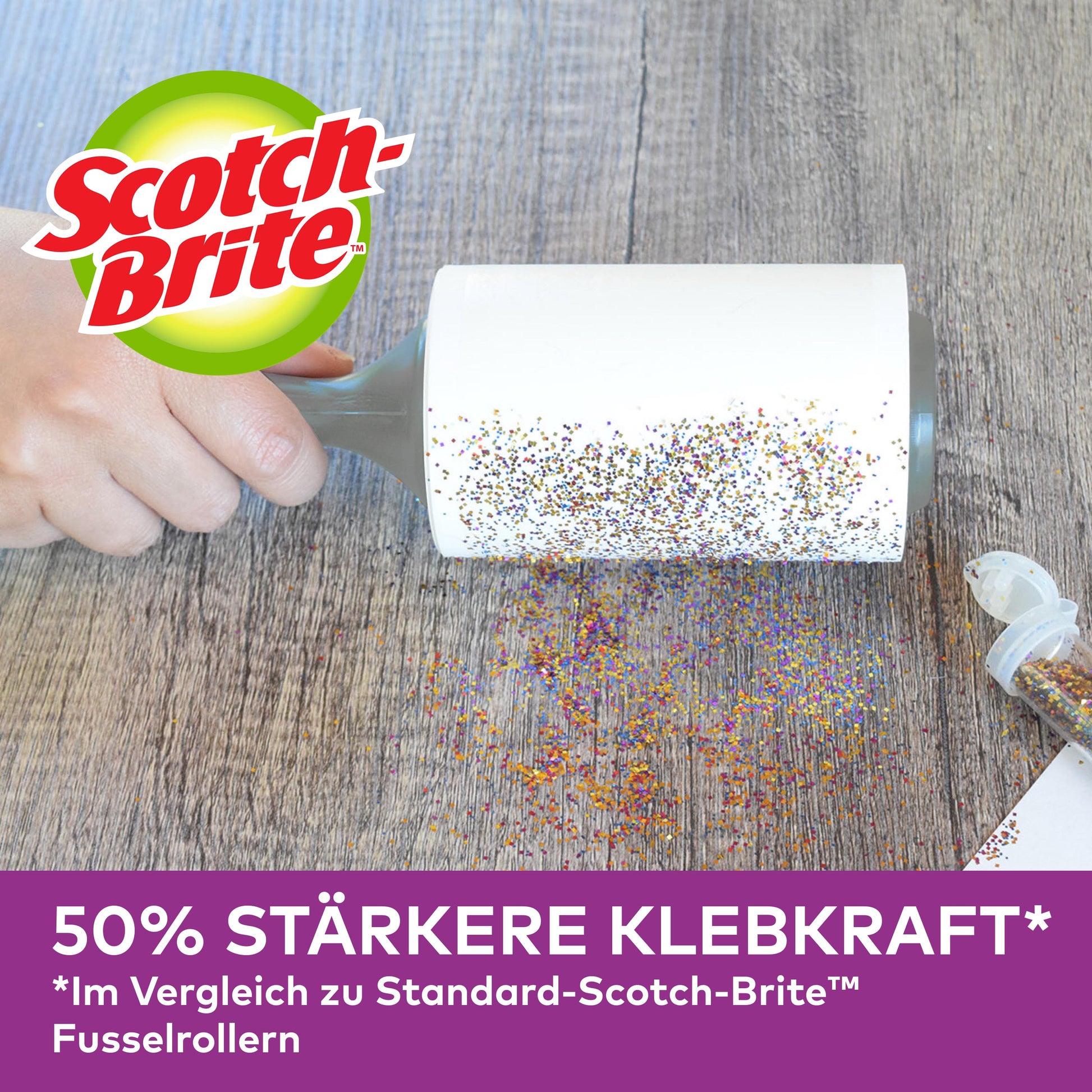 Eine Hand nutzt den Scotch-Brite™ Pet Extra Sticky* Roller für Tierhaare von 3M Deutschland GmbH (48 Blatt), um verschüttete Glitzer auf einer Holzoberfläche zu entfernen. Deutsche Werbung: 50 % stärkere Klebkraft als Standardmodelle.