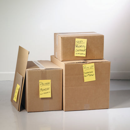 Vier auf einem hellen Boden gestapelte Pappkartons, jeder beschriftet mit 3M Deutschland GmbH Post-it® Super Sticky Notes im Großformat, Ultra Gelb (101 x 152 mm), mit Anweisungen wie "Deliver Monday" und "Ship Priority Overnight".