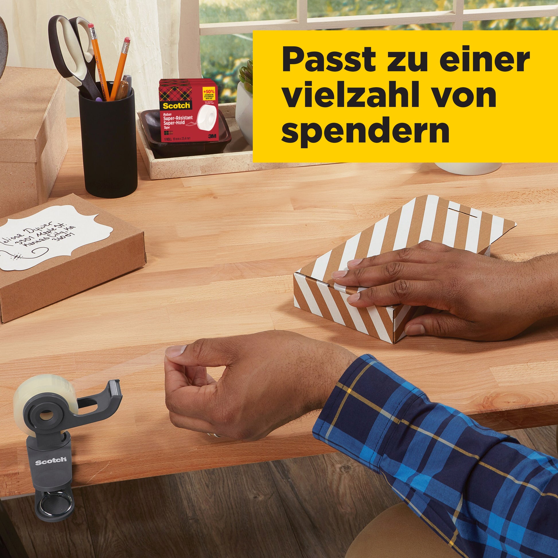 Eine Person in einem blau karierten Hemd verschließt eine braun-weiß gestreifte Schachtel mit Scotch® Super-Hold Secure Tape (1 Rolle, 19 mm x 25,4 m) der 3M Deutschland GmbH auf einem Holztisch. In der Nähe befinden sich ein Klebebandabroller, eine Nachfüllpackung und Schreibutensilien.