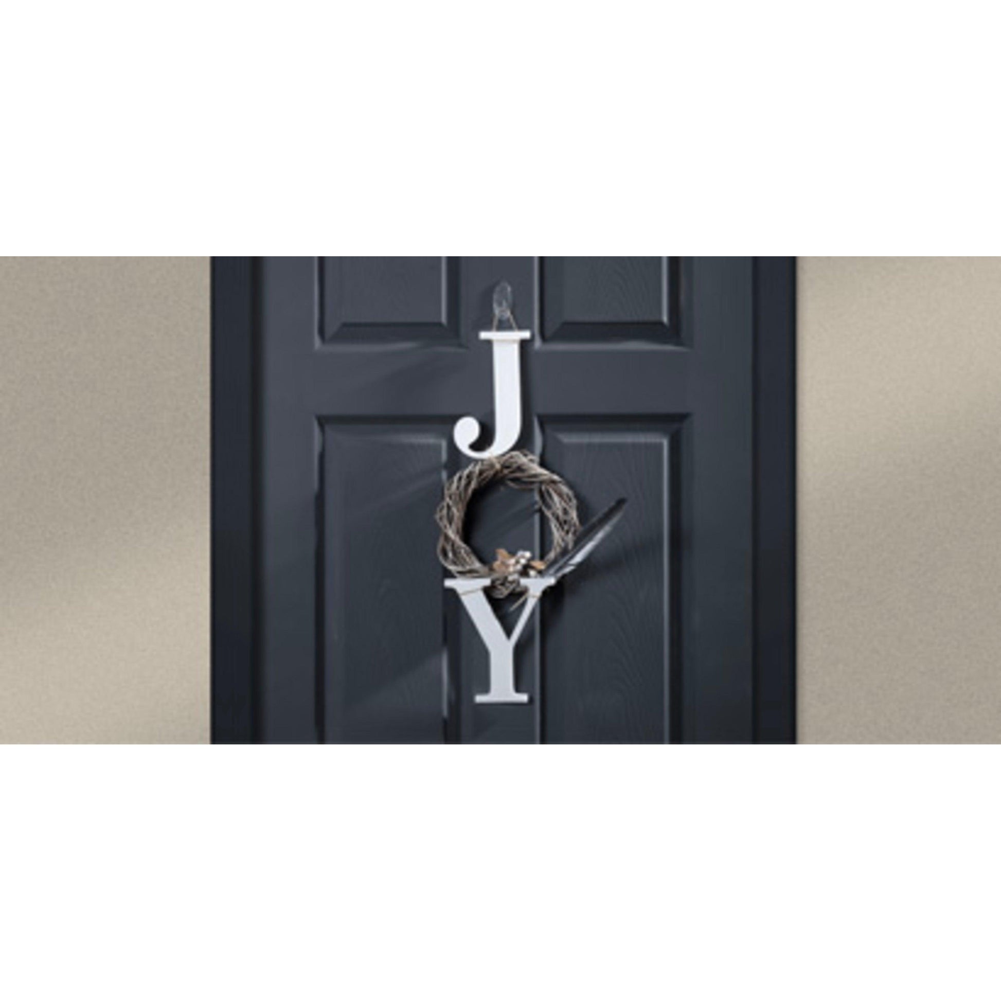Eine schwarze Tür zeigt große weiße Buchstaben "J" und "Y" mit einem kleinen braunen Kranz - aufgehängt von einem 3M Deutschland GmbH Command™ transparenter, mittelgroßer, ovaler Haken (Außenbereich, 17091AW) - dazwischen, um "JOY" zu schreiben. Der Hintergrund ist eine schlichte hellbraune Wand.