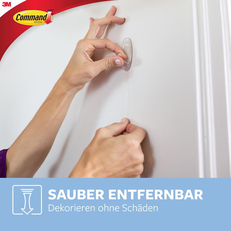 Henkilö irrottaa läpinäkyvän Command™ Koukku M, keskikokoinen, 17091CLR 3M Deutschland GmbH:sta valkoiselta seinältä. Command ja 3M logot ovat vasemmassa yläkulmassa. Alhaalla lukee: "Helppo irrottaa. Koristele ilman vahinkoa."