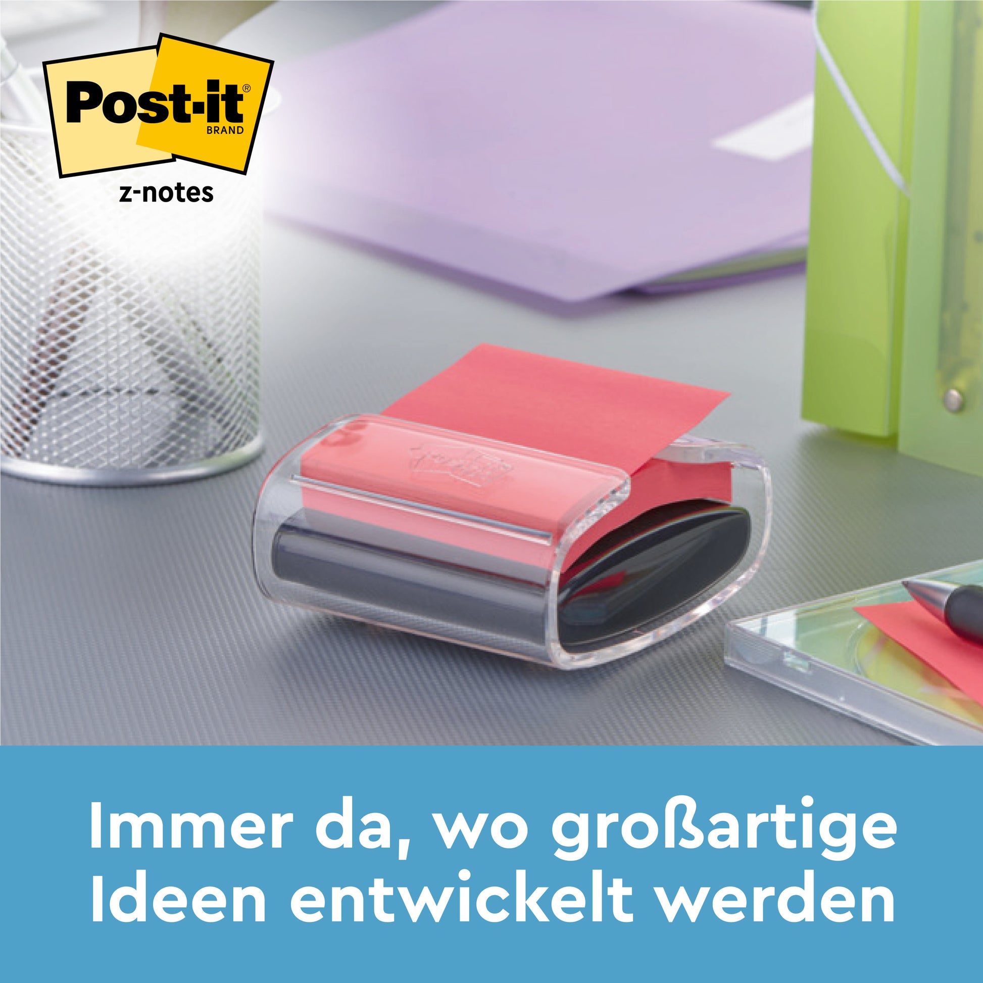 Ein weißer, bärenförmiger Post-it® Z-Notes Dispenser der 3M Deutschland GmbH mit blauen Super Sticky Z-Notes (76x76mm, 2 Blöcke, je 45 Blatt) steht auf einem Schreibtisch neben einem Stifthalter, einem lila Ordner und Klebeband. Deutscher Text: "Immer da, wo großartige Ideen entwickelt werden.