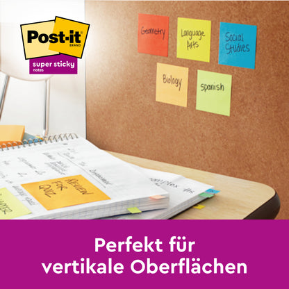 Eine Korkplatte mit 3M Deutschland GmbH Post-it® Super Sticky Notes (76 mm x 76 mm, 45 Blatt/Block, 100% PEFC) mit den Beschriftungen Geometrie, Sprachunterricht, Sozialkunde, Biologie und Spanisch liegt auf einem Schreibtisch. Text: "Perfekt für vertikale Oberflächen.