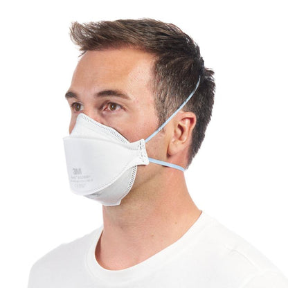 Mies yksinkertaisessa valkoisessa paidassa käyttää 3M™ Aura™ mukavuushiukkasnaamaria 9320+ FFP2 hengityssuojainta ilman venttiiliä 3M Deutschland GmbH:lta, kahdella päänauhalla ja hieman vasemmalle suunnattuna.