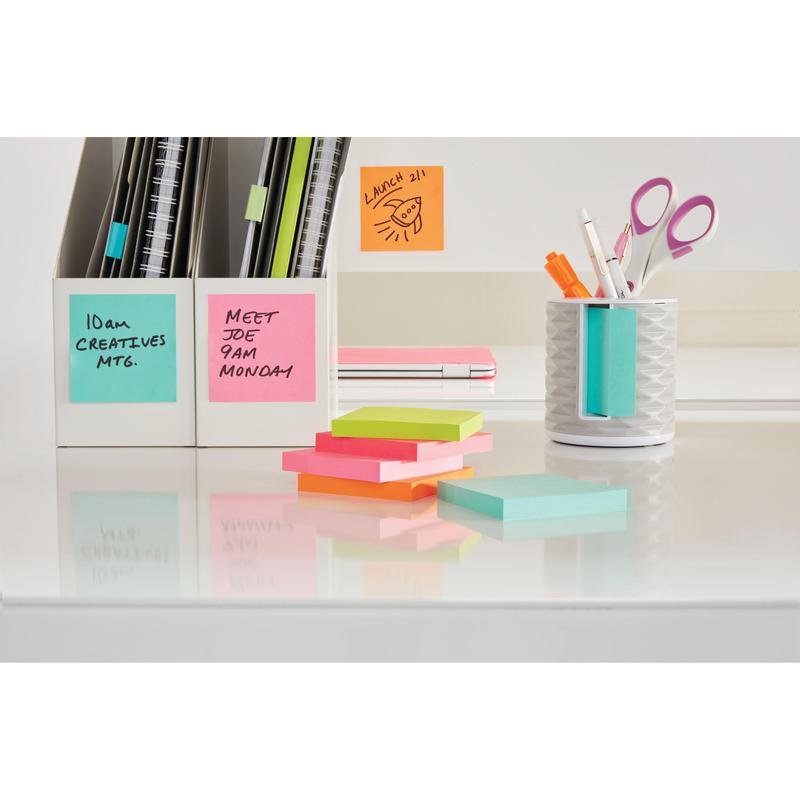 Siisti työpöytä, jossa on Post-it® Super Sticky Z-Notes (76 x 127 mm, 100% PEFC) 3M Deutschland GmbH:lta merkittyihin kansioihin, muistutuksiin seinällä ja pöydällä sekä teline, jossa on kyniä, saksia ja värikkäitä muistilappulohkoja.