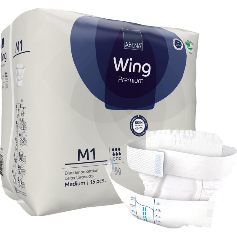 Abena Re-Seller GmbH:n ABENA Wing Premium -pakkaus on kuvattu edessä avattuna pehmusteena, joka tarjoaa suojaa ja mukavuutta. Pakkauksessa lukee, että se sisältää 15 keskikokoista pehmustetta rakonsuojaksi.