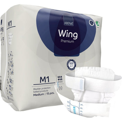 Abena Re-Seller GmbH:n ABENA Wing Premium -pakkaus on kuvattu edessä avattuna pehmusteena, joka tarjoaa suojaa ja mukavuutta. Pakkauksessa lukee, että se sisältää 15 keskikokoista pehmustetta rakonsuojaksi.