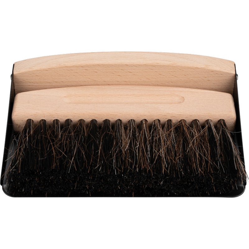 Puinen varrellinen harja ja tummat harjakset istuvat mustalla rikkalapiolla - ihanteellinen kuten ENA Living pöytäharja- ja rikkalapiosetti Abena Re-Seller GmbH:lta (24 kpl laatikko) helppoon pöydän puhdistukseen.