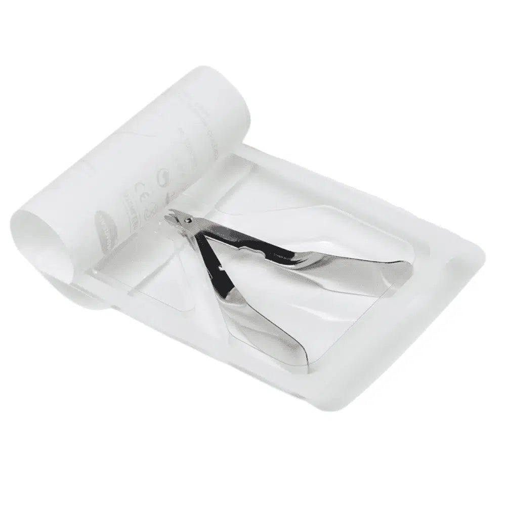 Der Auslaufartikel: Hartmann Klammerentferner 10 cm der Paul Hartmann AG liegt auf einem weißen Einwegtablett mit einem gerollten Papierblatt daneben, was auf die Verwendung im medizinischen oder manikürischen Bereich hinweist. (Verpackung: 1 Stück).