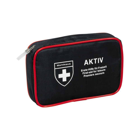 Kompakti musta ensiapupakkaus, jossa on punaiset reunukset ja vetoketju, valkoinen risti-logo sekä tekstit ”Holthaus Medical AKTIV” ja ”Erste-Hilfe für Freizeit / First-aid for Leisure / Premiers secours” etupuolella. Sopii erinomaisesti sekä matkalle että kotiin.