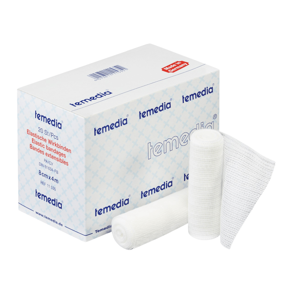 Laatikko Holthaus Temedia® Wirkbinde, 10 cm x 4 m | Pakkaus (20 kappaletta) Holthaus Medical GmbH & Co. KG:ltä on esillä, ja tuotteen nimi ja yksityiskohdat ovat näkyvissä pakkauksessa. Vieressä on kaksi rullattua joustavaa sidettä ja avattu pala sideharsoa. Pakkaus on sinivalkoinen, punaisella tekstillä, joka ilmoittaa lääketieteelliset tuotetiedot.