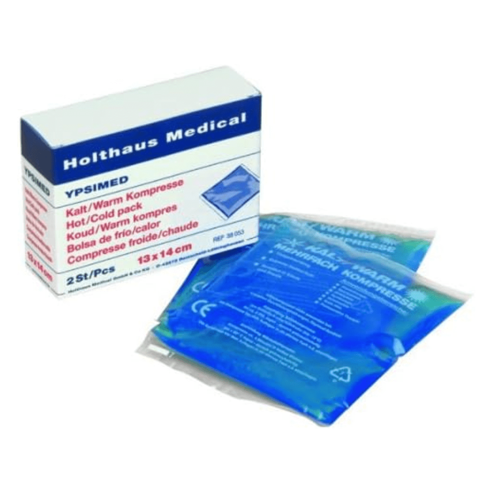 Kuvassa on laatikko, jossa on teksti „Holthaus YPSIMED kylmä / lämmin kompressi 13 x 14 cm | Pakkaus (2 kappaletta)“ Holthaus Medical GmbH & Co. KG:ltä. Sisällä on kaksi kompressia, kumpikin kooltaan 13 x 14 cm, ja ne on kääritty läpinäkyvään muoviin, joka sisältää sinistä nestettä. Laatikon teksti on monikielinen ja korostaa tuotteen kuuma- ja kylmäkäyttöä, joka on välttämätöntä ensiaputilanteissa.