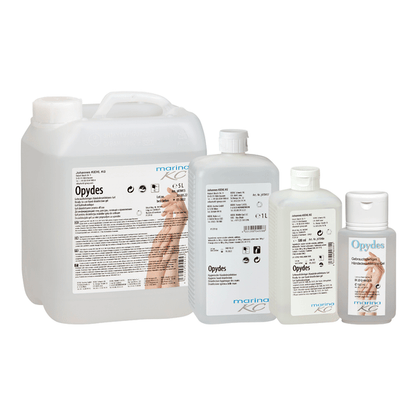 Kuvassa on neljä kirkasta pulloa Kiehl Opydes Hygienische Händedesinfektion Johannes Kiehl KG:ltä eri kokoisina rivissä. Niissä on valkoinen ja sininen teksti sekä käsisymbolit hygieniseen käsien desinfiointiin ja mikrobien vähentämiseen.