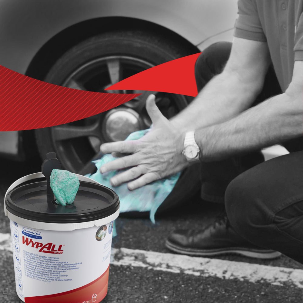 Henkilö polvistuu puhdistamaan autonrenkaita vihreillä WypAll® pyyhkeillä Kimberly-Clark GmbH:lta. Etualalla on näkyvä kontti, jossa on 6 sankoa x 90 arkkia. Mustavalkoisessa taustassa on voimakas punainen graafinen aksentti.