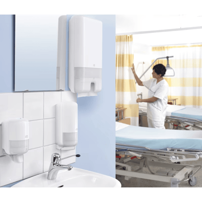 Sairaalahuoneessa seisoo lääkäri valkoisessa univormussa sängyn vieressä. Etualalla on pesuallas, jossa on Tork Xpress® 552000 -annostelija Multifold-käsipyyhkeille H2 TORK - Essity Professional Hygiene Germany GmbH:lta. Huone on varustettu lääketieteellisillä laitteilla ja keltaisilla raidallisilla verhoilla.