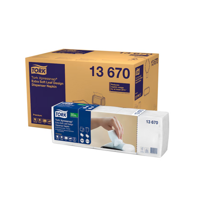 Tork Xpressnap® 13670 -annostelijaliinasäiliö, jossa on erityisen pehmeä lehtikuvio ja TORK-brändi Essity Professional Hygiene Germany GmbH:ltä, näytetään pakkauksen vieressä, jossa käsi vetää lautasliinan annostelijasta.