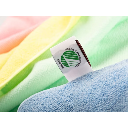 Lähikuva Vileda Professional MicroTuff Plus -pyyhkeen kangasmerkistä, jossa on Nordic Swan Ecolabel -symboli. Pyyhe on pehmeissä sävyissä keltaisena, vaaleanpunaisena, vihreänä ja sinisenä näkyvällä rakenteella, mikä tekee siitä ihanteellisen ammattimaiseen puhdistukseen. Se on Vileda GmbH:n valmistama ja tunnettu kestävänä mikrokuituliinana.