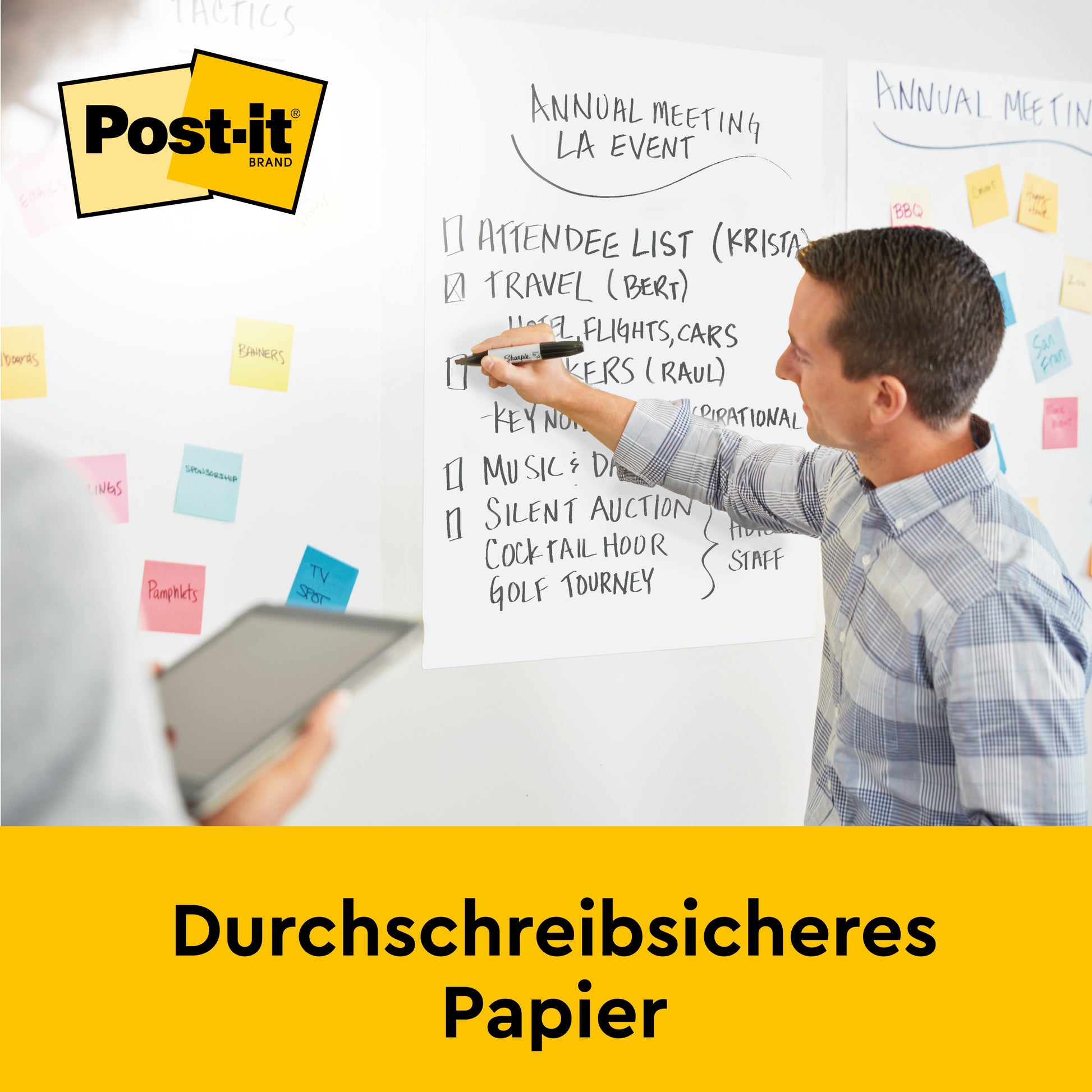 Während eines Meetings zeigt ein Mann mit einem Marker auf ein Post-it® Super Sticky selbsthaftendes Meeting Chart/Flipchart 559P von 3M Deutschland GmbH. Eine andere Person hält ein Tablet, auf dem bunte Super Sticky Meeting Notes in Neonfarben an der Wand angebracht sind.