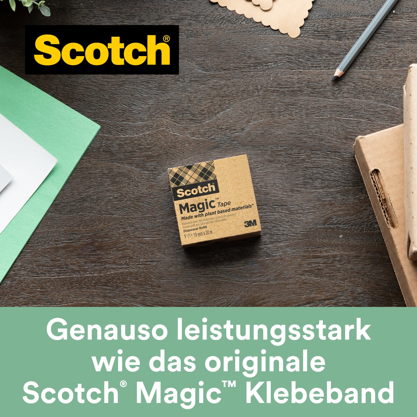 Eine Schachtel Scotch® Magic™ Klebeband von 3M Deutschland GmbH (19 mm x 33 m, 9 Rollen/Packung, mit 66 % pflanzlichem Klebstoff) liegt auf einem Holztisch neben grünem und weißem Papier, einem Notizbuch und einem Stift - perfekt für umweltbewussten Bürobedarf.