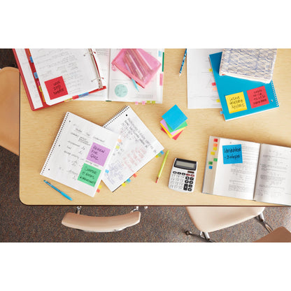 Ein Tisch in einem Klassenzimmer, ordentlich angeordnet mit offenen Heften, Lehrbüchern, einem Taschenrechner, farbigen Stiften, Ordnern und Post-it® Notes aus der Energetic Collection (38mm x 51mm, 100 Blatt/Block), Marke: 3M Deutschland GmbH; drei leere Stühle umgeben den Tisch.