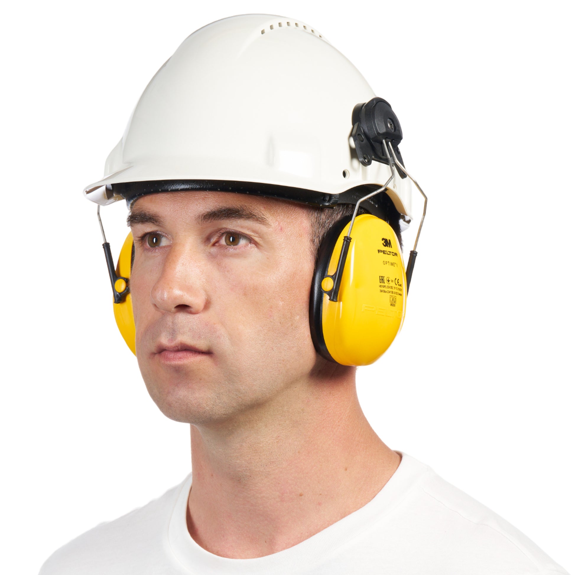 Ein Mann trägt einen weißen Schutzhelm und 3M™ PELTOR™ Optime™ I Kapselgehörschützer für Helme (H510P3E, SNR 26 dB, gelb) von 3M Deutschland GmbH und blickt mit neutralem Gesichtsausdruck vor weißem Hintergrund nach vorne.
