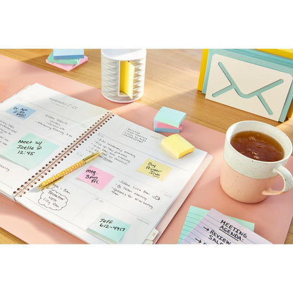 Avoin suunnittelija käsinkirjoitetuilla muistiinpanoilla on pöydällä, jota ympäröivät kynä, tee, kortit, postijärjestäjä ja 3M Deutschland GmbH:n Post-it® kierrätetyt Z-muistiinpanot (76 mm x 76 mm, 100 arkkia/lohkare, 100% PEFC).