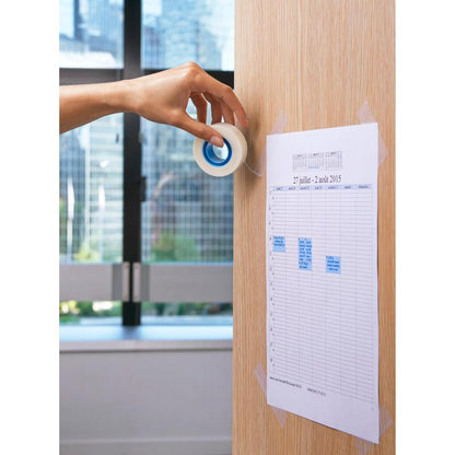 Käsi käyttää 3M Deutschland GmbH:n Scotch® näkymätöntä teippiä (19 mm x 33 m) kiinnittääkseen tulostetun suunnitelman vaalealle puuseinälle. Taustalla ikkuna näyttää näkymän kaupunkimaisemaan.