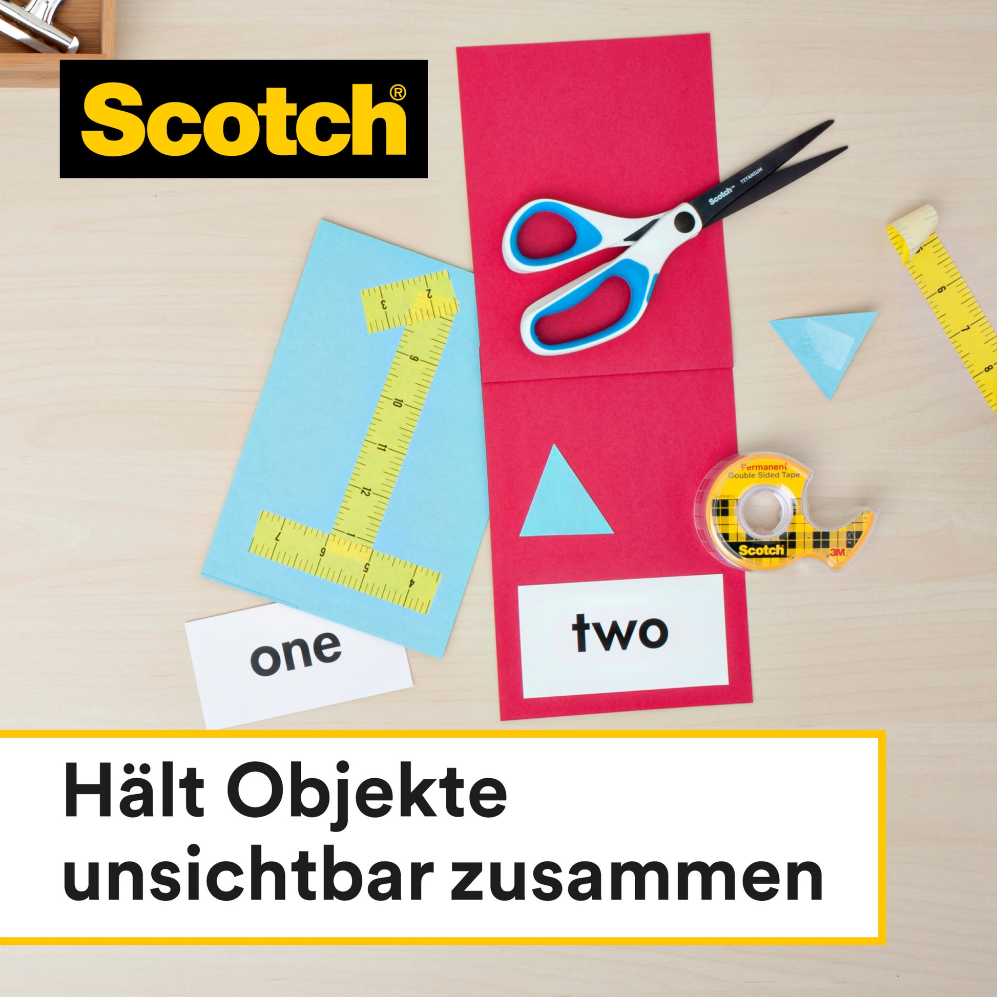 Auf einem hellen Holztisch liegen eine Schere, ein gelbes Lineal, Papierdreiecke und zwei Karten ("eins", "zwei") neben einer Rolle Scotch® doppelseitiges Klebeband von 3M. Text: "Hält Objekte unsichtbar zusammen.