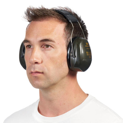 Mies, jolla on lyhyet ruskeat hiukset, yksinkertaisessa valkoisessa paidassa, käyttää suuria vihreitä 3M™ PELTOR™ Optime™ II H520A -kuulonsuojaimia (SNR 31 dB, 1 kappale) 3M Deutschland GmbH:lta, hieman vasemmalle käännettynä valkoista taustaa vasten.